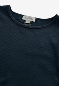 Navyblauwe zwangerschapstop met ribbeltextuur. Voorzien van een ronde halslijn en een label met de tekst "NEXT." Zacht, rekbaar materiaal voor comfort.
