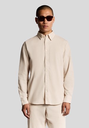 Helle beige Langarmbluse mit einem Button-Down-Kragen, aus einem glatten Stoff gefertigt. Verfügt über einen geraden Saum und kontrastierende Knöpfe.