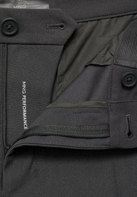 Pantaloni da uomo neri in tessuto liscio, dotati di chiusura con cerniera e bottone, con etichetta interna e dettagli delle tasche.