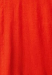 Tessuto rosso brillante con una superficie liscia e una leggera lucentezza, caratterizzato da un design uniforme e semplice, privo di modelli o decorazioni.