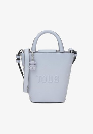 Light blue leather handbag with top handles, shoulder strap, embossed "TOUS" logo, and small bear-shaped charm attached to the strap.