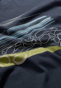 Camiseta de algodón azul marino con patrones abstractos de líneas y piedras en azul claro y verde, con una textura suave y un ajuste relajado.