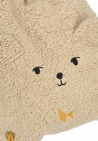 Beige plyschväska med en texturerad yta, prydd med ett broderat ansikte med svarta ögon och näsa, samt en gul rosettdetalj på framsidan.