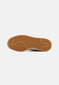 Sneaker sole, gum rubber material with a zigzag tread pattern. Slightly rounded shape and clean edges. Predominantly brown with subtle texture.