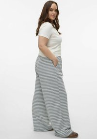 Pantalones de pierna ancha a rayas en tela gris y blanca, con cintura elástica y bolsillos laterales, combinados con una camiseta blanca sencilla.