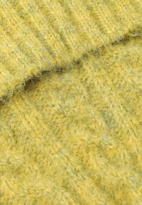 Sárga kötött szövet, amely textúrázott mintával rendelkezik, jól látható szálakkal. A dizájn bordás és szövet részeket is tartalmaz, hangsúlyozva a meleget.