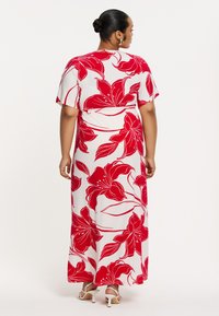 Maxikleid mit weißem Grund und auffälligen roten Blumenmustern, kurzen Ärmeln, tailliertem Schnitt und fließendem Rock. Details umfassen einen glatten Stoff und knöchellänge.