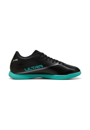 Schwarzer und tealfarbener flacher Indoorsoccer-Schuh mit Schnürsenkeln, strukturiertem Design, "ULTRA" Text und Puma-Logo an der Ferse.