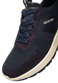 Navyblaue Sneakers mit einem oberen Teil aus Mesh und Suede-Akzenten, GORE-TEX Branding und einer beigen Gummisohle mit strukturierten Details.