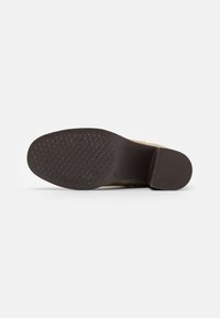 Brown footwear sole with textured grip pattern and curved heel design. Underside features diamond-shaped tread for traction.