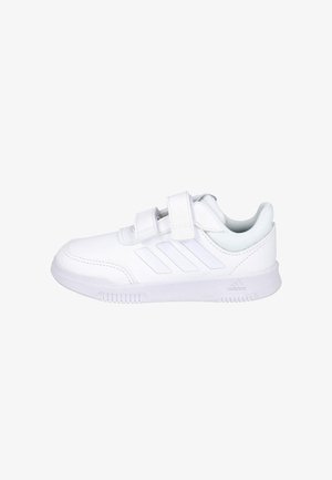 Zapatilla blanca Adidas con dos tiras de velcro, tres franjas laterales, cuello acolchado y suela texturizada, mostrada de perfil.