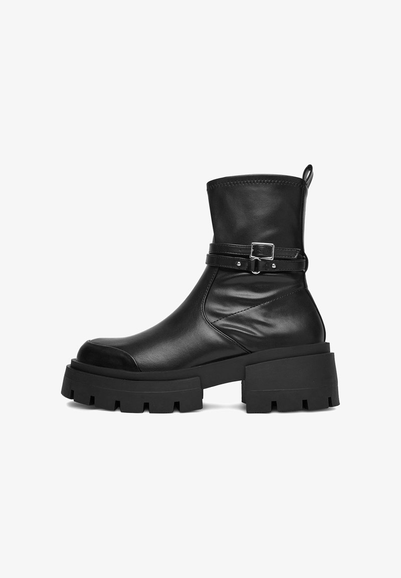 Melna ādas potīšu zābaku ar masīvu griezumu, bloku papēdi, noapaļotu purngalu un dekoratīvo siksniņu ar sudraba sprādzi ap potīti.