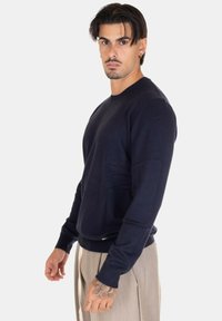 Maglione lavorato a maglia blu navy con scollo rotondo, maniche lunghe, polsini a costine e vestibilità comoda; decorato con sottili dettagli di cucitura.