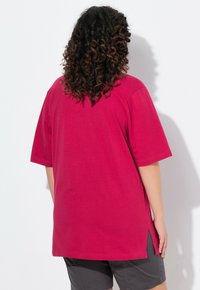T-shirt oversize fucsia con maniche corte, aperture laterali e orlo arrotondato. Realizzato in morbido cotone, progettato per comfort e facilità.