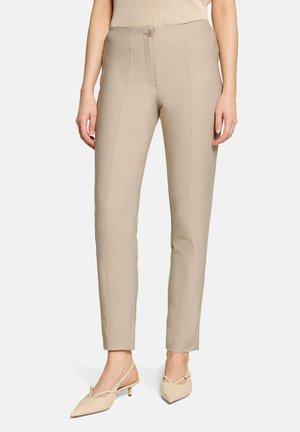 Beige broek met rechte pijpen en details in de voornaad, sluiting met knoop en rits, gedragen met beige slingback kittenhakken.