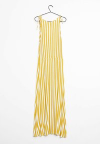 Żółto-biała w paski, bezrękawna sukienka maxi z węzłami na ramionach, wisząca na czarnym wieszaku na białym tle.