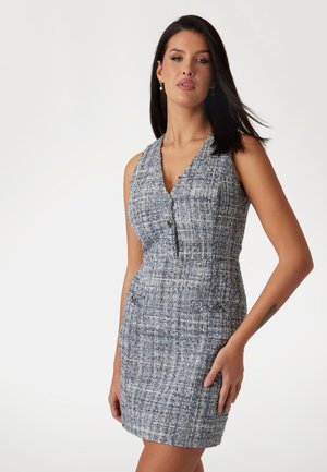 Abito senza maniche, aderente, realizzato in tessuto tweed blu. Presenta un collo a V, bottoni frontali e doppi taschini frontali con dettagli metallici.
