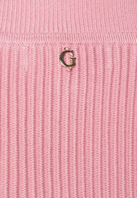 Różowa prążkowana tkanina dzianinowa z złotym akcentem w postaci logo "G", charakteryzująca się teksturowanym wzorem i równomiernie rozmieszczonymi pionowymi liniami.