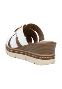 White wedge sandal featuring cut-out straps, a brown textured platform sole, and a stitched accent along the edge.