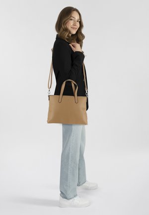 Una borsa a mano in finta pelle di colore beige con due manici superiori e una tracolla removibile, caratterizzata da una forma rettangolare elegante e dettagli minimi.
