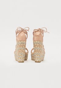 Beige høyhælte sandaler med ankelbånd og flettede jute kile såler. Sølvdetaljer vever seg gjennom juten for ekstra detaljer.