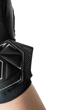 Gros plan sur le bras d'une personne portant une attelle de poignet Neusch noire avec un support texturé et une sangle ajustable sur fond blanc.