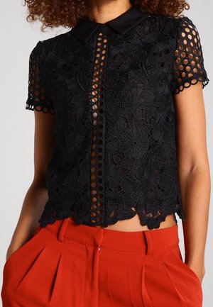 Zwarte kanten blouse met een kraag, bloemenpatroon, korte mouwen en open cirkelvormige uitsnijdingen, voorzien van een gegolfde zoom.