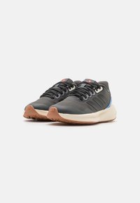 Zapatillas deportivas negras y grises con una parte superior texturizada, detalles en azul y suela beige clara. Presentan un diseño seguro con cordones y suela de goma con dibujo.