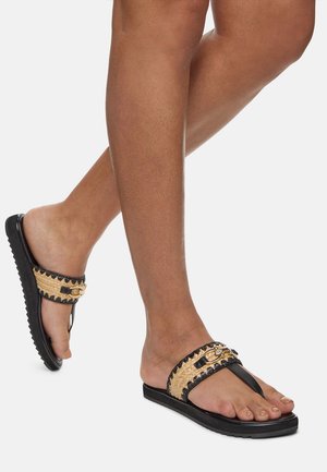 Black and tan flip-flops with a woven strap, decorative gold accents, and a textured black sole.