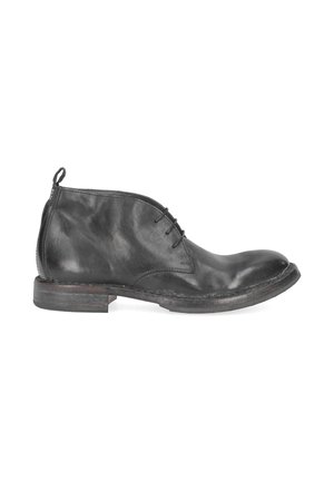 Bottine en cuir noir avec trois œillets, bout arrondi, languette au talon et semelle basse en bois superposé.
