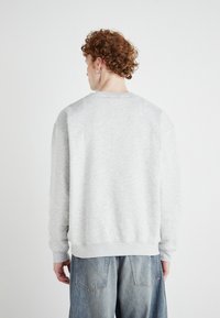 Sweatshirt gris à col rond avec une coupe décontractée, des poignets et un ourlet côtelés. Tissu doux et texturé. Couture discrète et aucune marque visible.