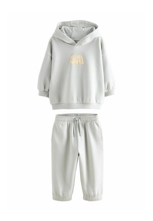 Ensemble de sweat à capuche et de joggings gris clair en tissu doux. Le sweat à capuche présente un motif à l'avant avec l'inscription "Cool Vibes" en beige clair. Poignets élastiques.