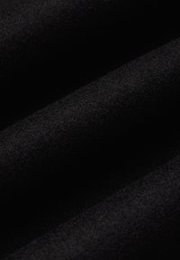 Czarna wełniana tkanina o miękkiej, fakturowanej powierzchni, prezentująca gładki spadek i subtelny połysk, z widocznymi włóknami i fałdami.