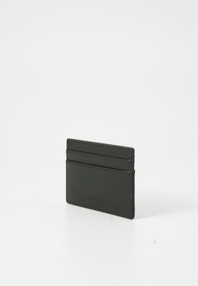 Black leather cardholder featuring four front slots, a smooth texture, and subtle logo detail on the front. Rectangular design.