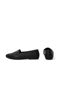 Zwarte loafers van leer met een gestructureerde afwerking, voorzien van een uitsparing aan de voorkant, gouden hardware-accent en een platte rubberen zool.