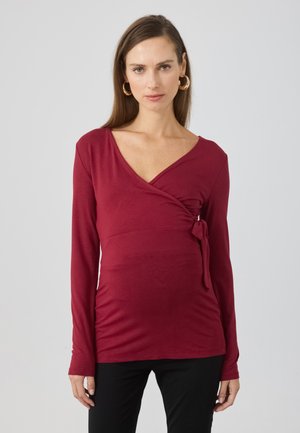 Burgundy long-sleeve wrap top with a deep V-neck and tie detail at the waist, made from soft, stretchable fabric.