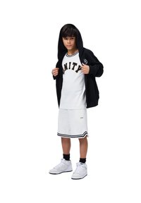Felpa nera con zip, T-shirt bianca con "UNITY" in nero, pantaloni corti bianchi con righe nere, calzini neri e sneakers bianche.