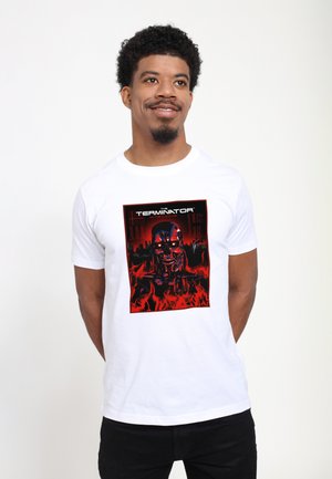 Hvid bomulds-t-shirt med et stort grafisk print af en robotfigur foran en rød og sort baggrund med flammer og tekst.