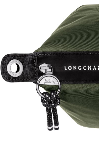 Green nylon bag with black leather accents, featuring a silver zipper, logo detail, and a braided black cord handle.
