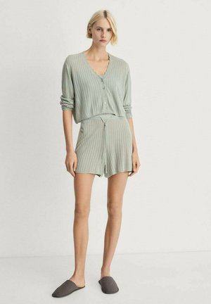 Set de loungewear tricotat în verde deschis, format dintr-o jachetă cu nasturi și decolteu în V, împreună cu pantaloni scurți asortați. Include papuci gri.