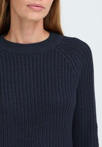 Pull en tricot bleu marine avec un col rond côtelé et un motif de point texturé, mettant en valeur un design confortable et décontracté.