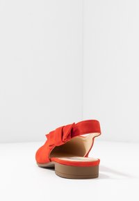 Red suede slingback shoe with a bow accent, rounded toe, and a low brown heel. Smooth interior with a cushioned insole.