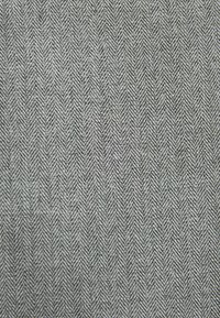 Tejido con un patrón de espiga en tonos de gris, con una textura suave y una construcción tejida para mayor durabilidad.