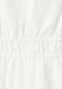 Tissu blanc avec motifs floraux brodés et coutures élastiques froncées créant une texture froncée dans la partie centrale.