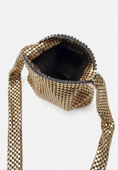 Sac à épaule en maille dorée métallique avec un intérieur noir. Comprend une bandoulière en chaîne et des accents circulaires le long du bord d'ouverture.