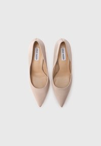 Γόβες από πατινέ δέρμα σε γυαλιστερό μπεζ χρώμα, με μυτερή μύτη και χαμηλό ντεσέν. Η εσωτερική επένδυση είναι μπεζ και φέρει το όνομα της μάρκας στις εσωτερικές σόλες.