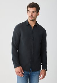 Schwarz langärmliges Hemd aus Leinen mit durchgehender Knopfleiste, Kragen und geradem Saum, kombiniert mit blauen Jeans.