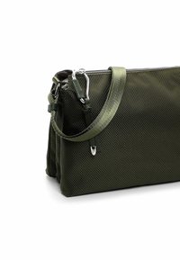 Zielona torba o teksturowanej powierzchni z zamknięciem na zamek, wyposażona w odpinany pasek i metalowe okucia. Kompaktowy, prostokątny kształt o strukturalnej formie.