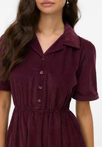Bordeaux corduroy jurk met een kraaghalslijn, korte opgerolde mouwen en een knoopsluiting aan de voorkant, voorzien van een gathered, elastische taille.