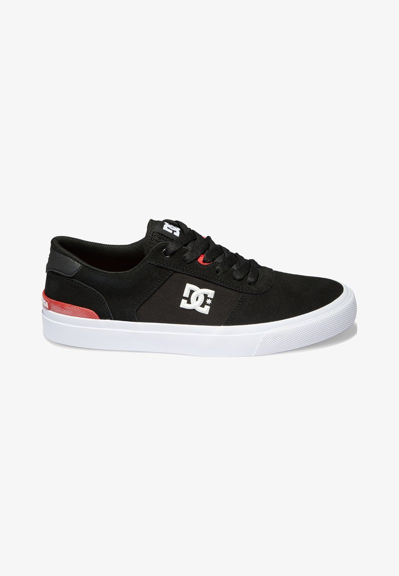 Black skate shoes with a suede upper, white rubber sole, red accents, and a white logo on the side. Round toe and lace-up design.